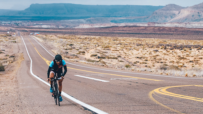 Image Of A Cyclist Riding On Desert Road To Increase Cycling Power