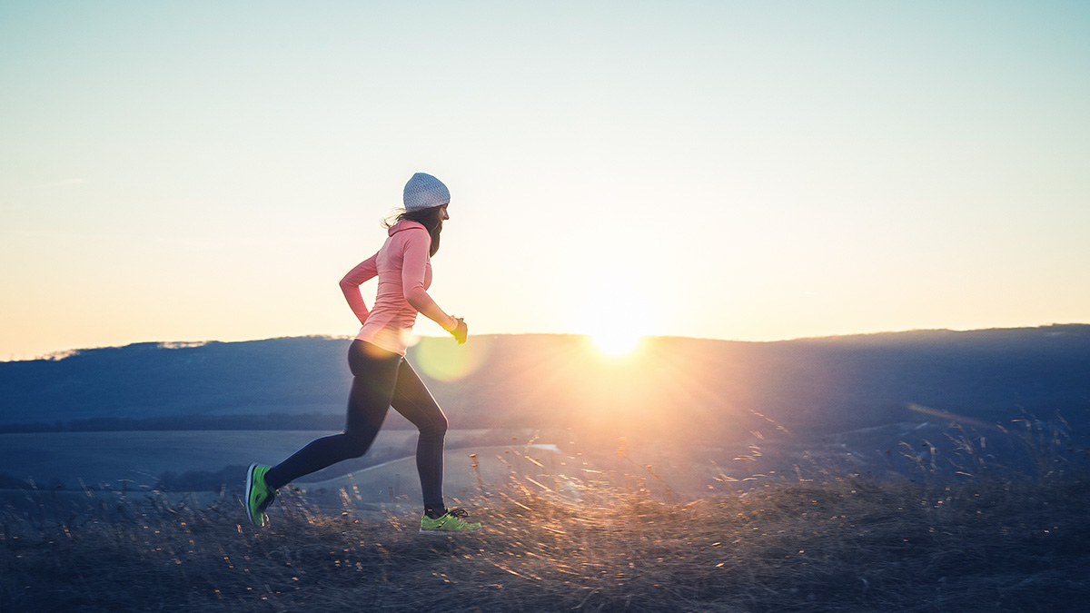 Image Of A Woman Trail Running In The Early Morning As A Running Base Training Workout