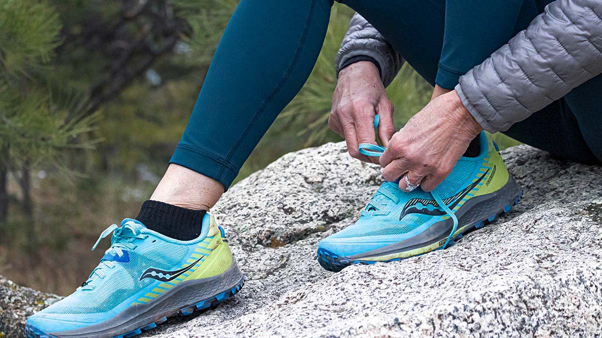 Close Up Of Runner Lacing Up Shoes On A Rock In The Mountains