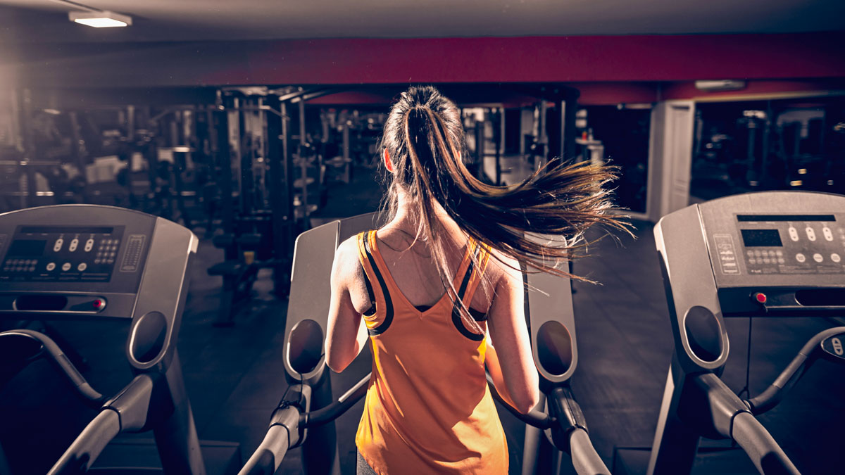 Sporty Woman Running On Treadmill. Gym Interior.