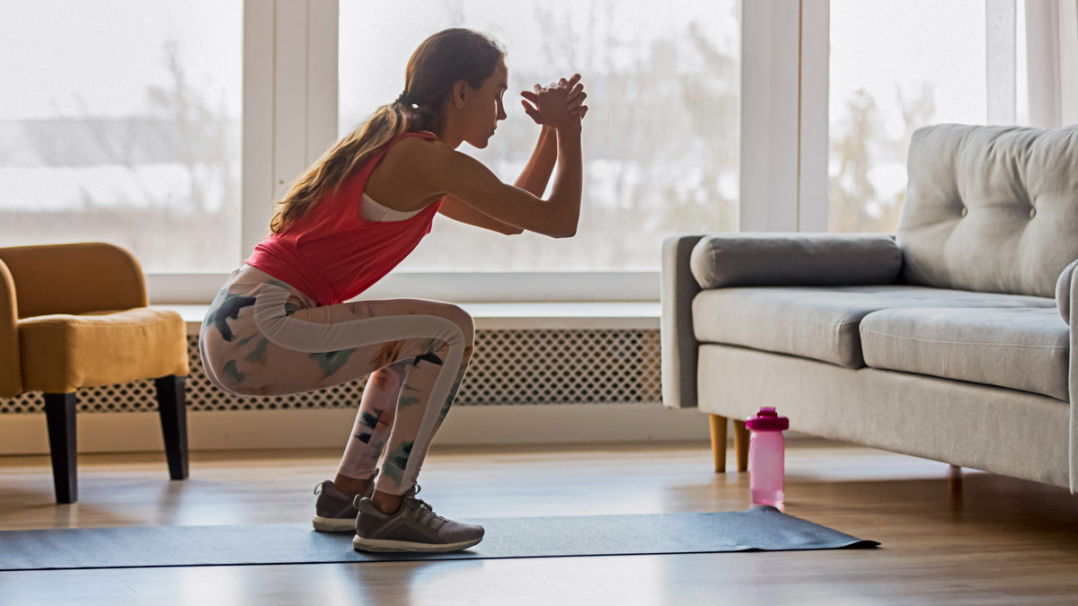 Sporty Young Woman Doing Squat Morning Exercise In Living Room