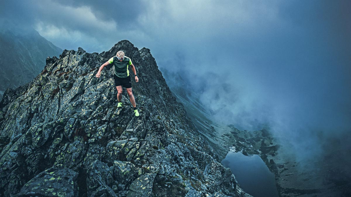 Trail Runner In Dark Evening Mountains, Rocks. Running In Storm