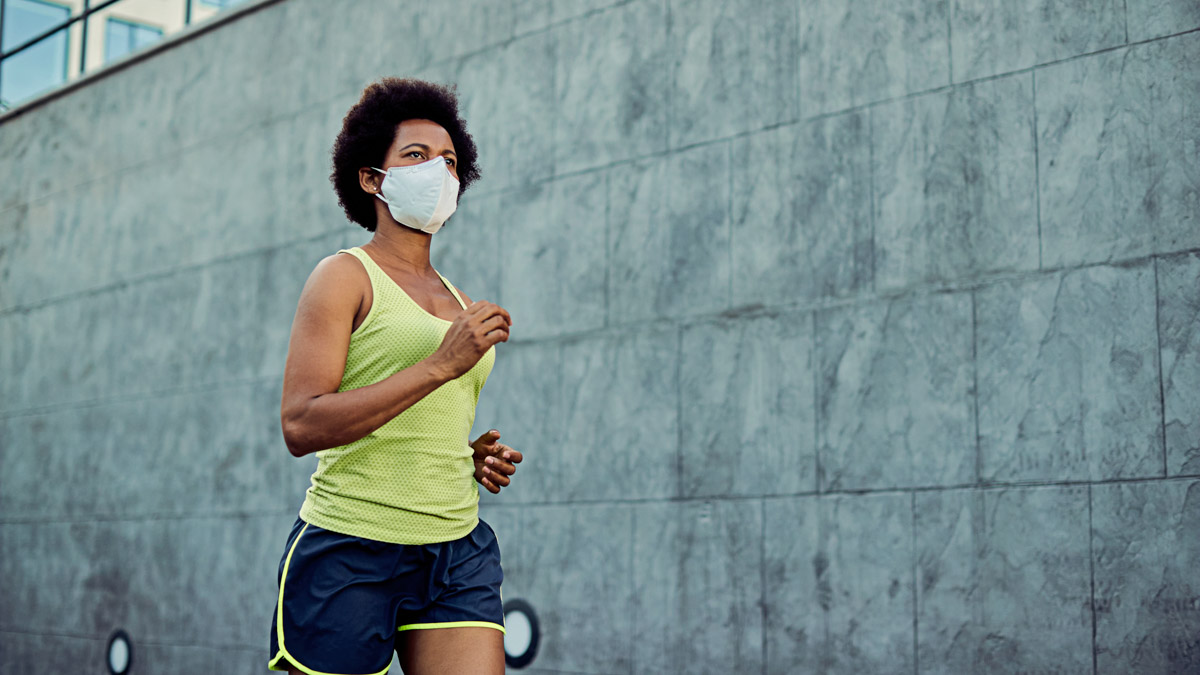 African American Athletic Woman Jogging While Wearing Protective Face Mask.