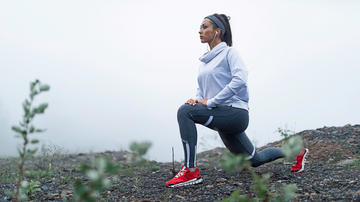 Young Athletic Woman Stretching Before A Trail Run In Foggy Weather