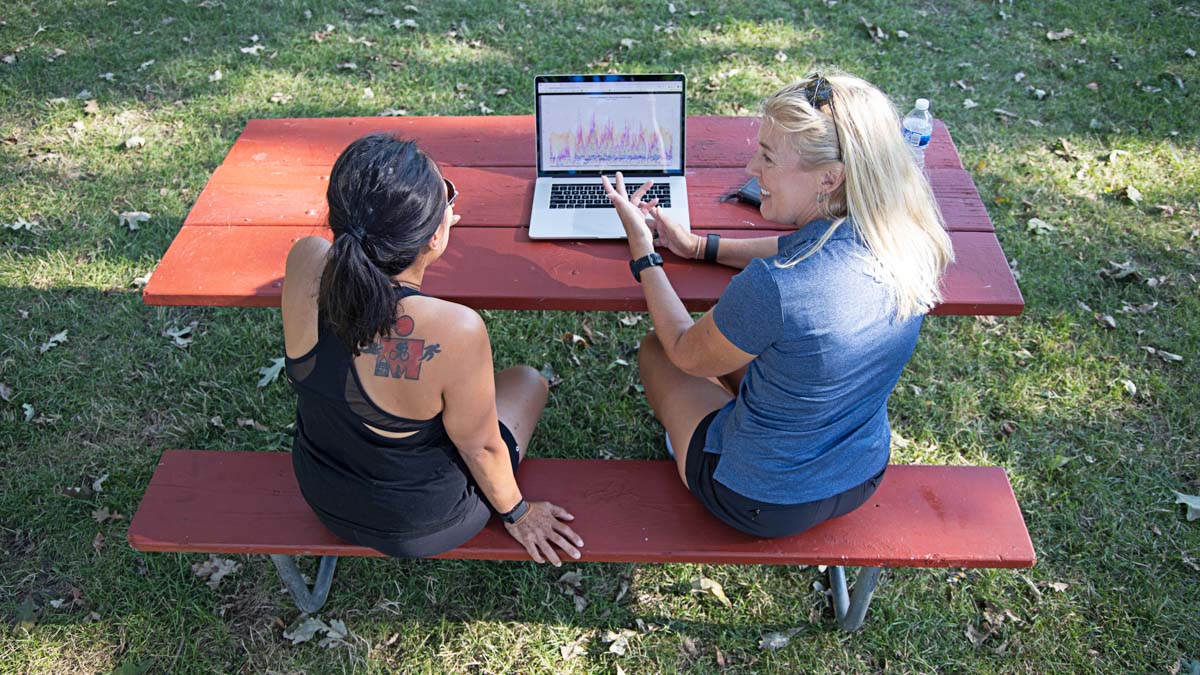 Endurance Coach Reviews Analytics On Laptop With Endurance Athlete With Ironman Tattoo