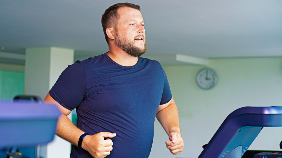 Slightly Overweight Man Exercising On Treadmill In Order To Obtain Sustainable Weight Loss
