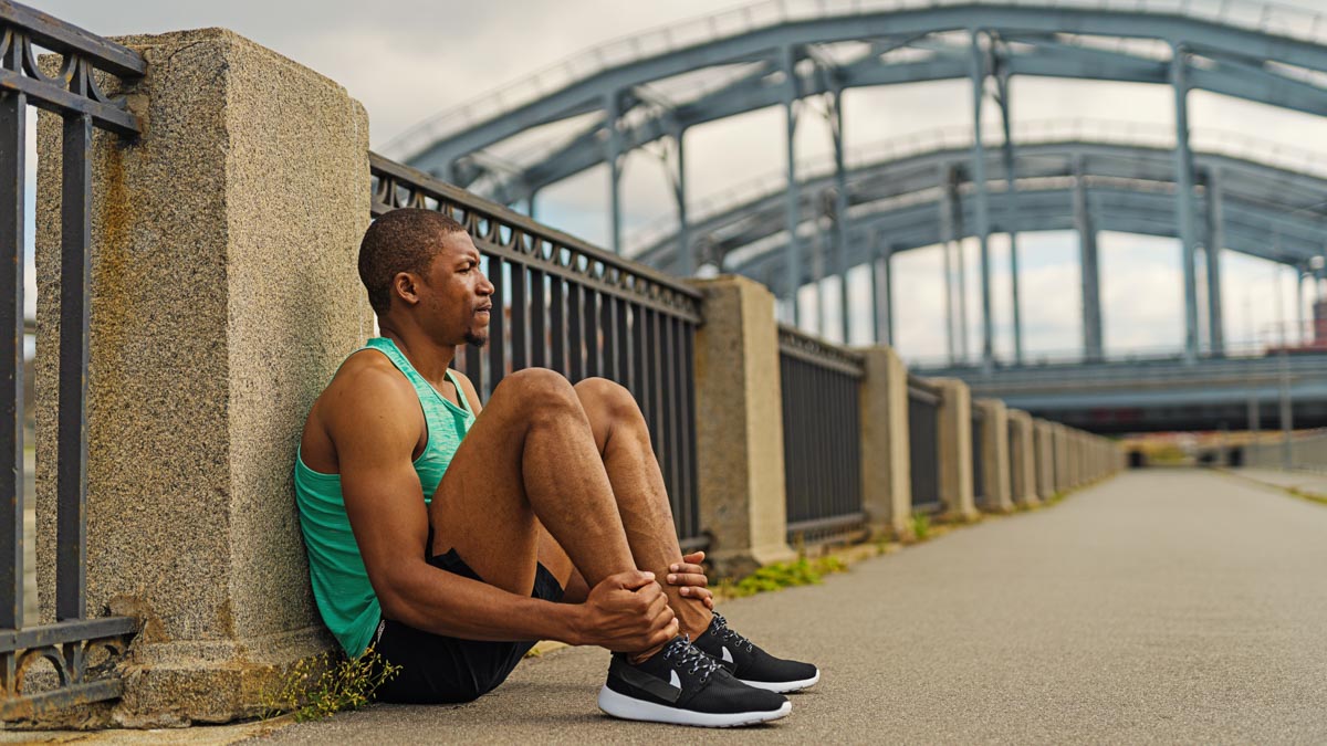 Male Runner Sitting On Bridge Reflecting On Mental Blocks And Mindset