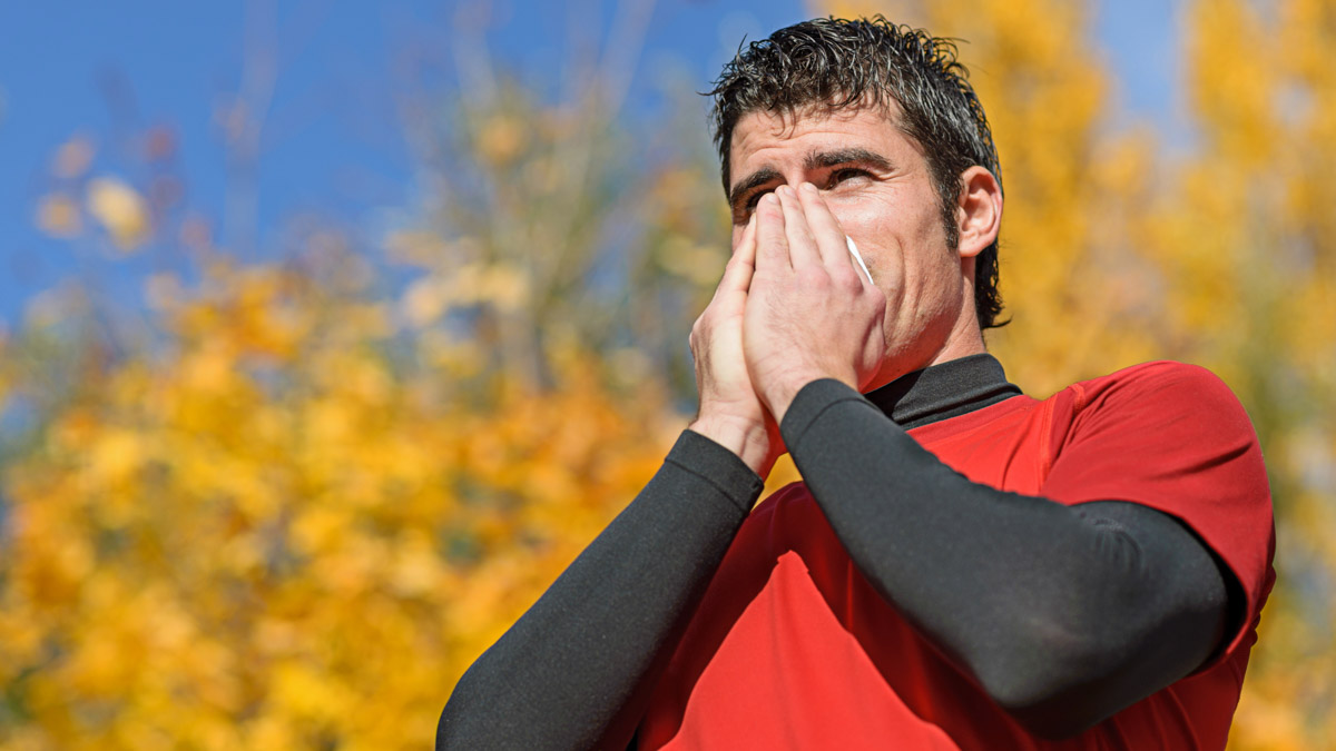 Male Athlete In Red Jersey Blows His Nose On A Run In A Fall Forest And Needs To Boost His Immune System