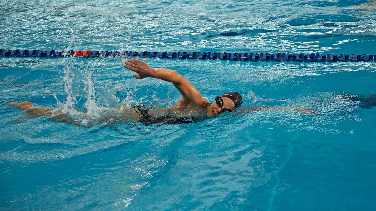 Swimmer Athlete Wearing Cap And Goggles Training Freestyle In Indoor Pool Practicing With Stroke Rate