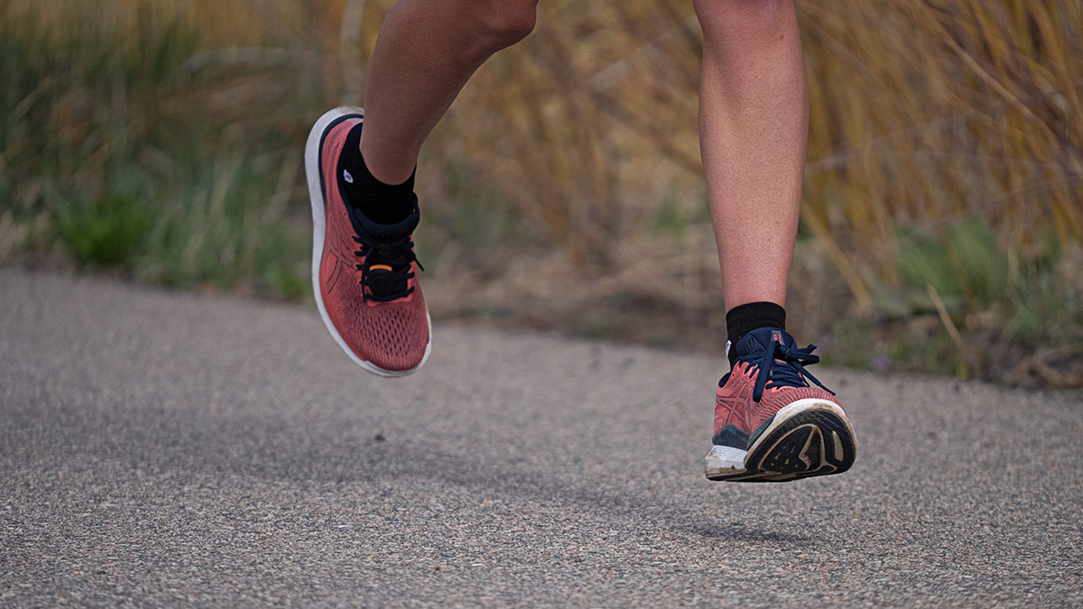 Image Of Runner's Legs And Feet From Knee Down Running On A Paved Road In Red Running Shoes