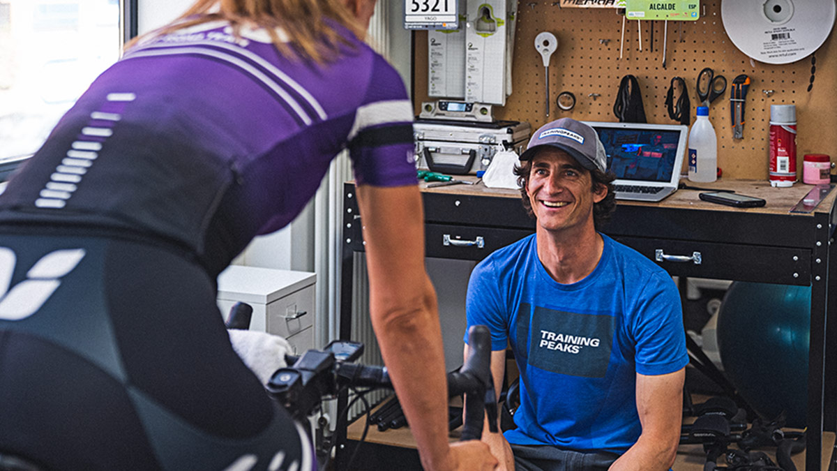 Trainingpeaks Coach Sits Across From Athlete On Stationary Bike And Prepares For The Offseason.