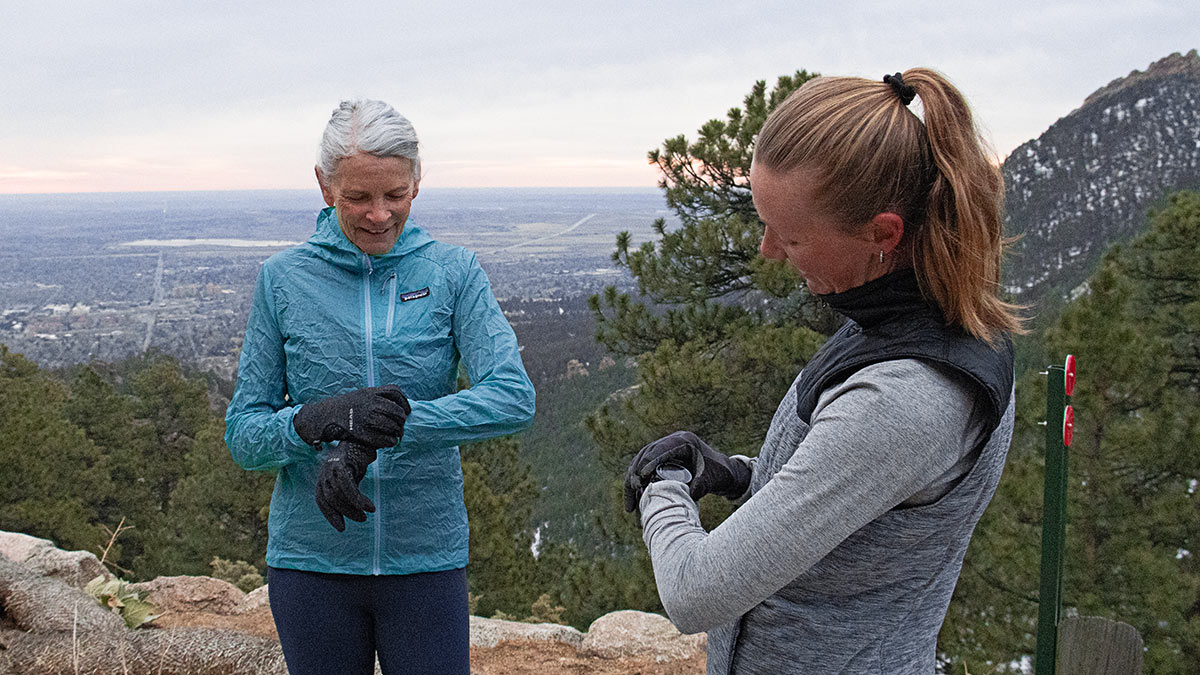 Two Women Endurance Athletes On Top Of Mountain Looking At Their Watches