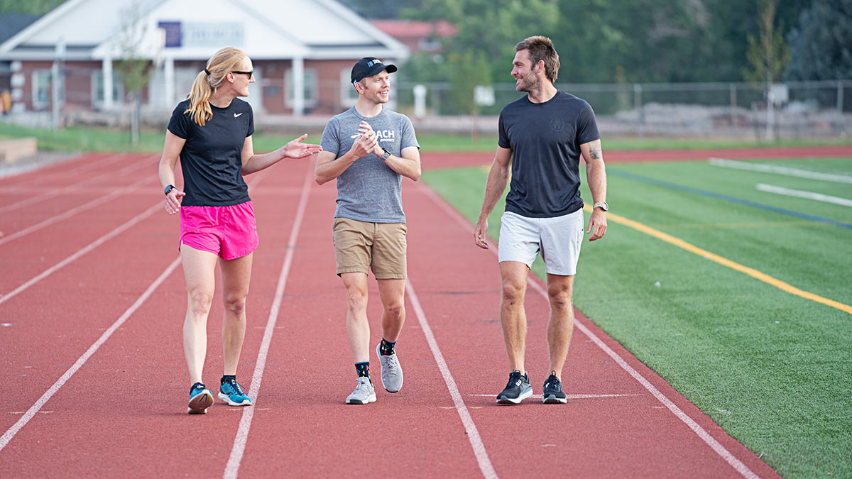 Picture Of Coach Walking With Two Athletes On The Straightaway Of The Track