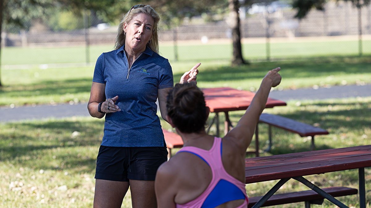 Female Endurance Coach Standing In Front Of Athlete And Guiding The Athlete On Training