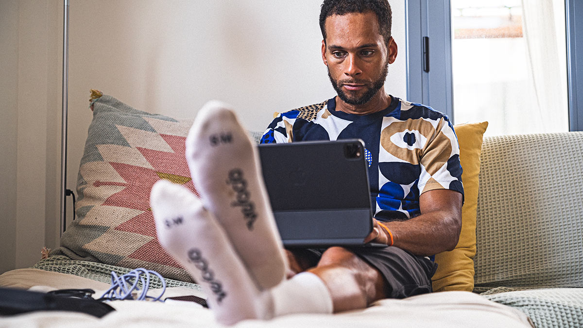 Image Of An Overtrained Male Cyclist Doing Research On His Laptop In Bed About How Long Does It Take To Recover From Overtraining?