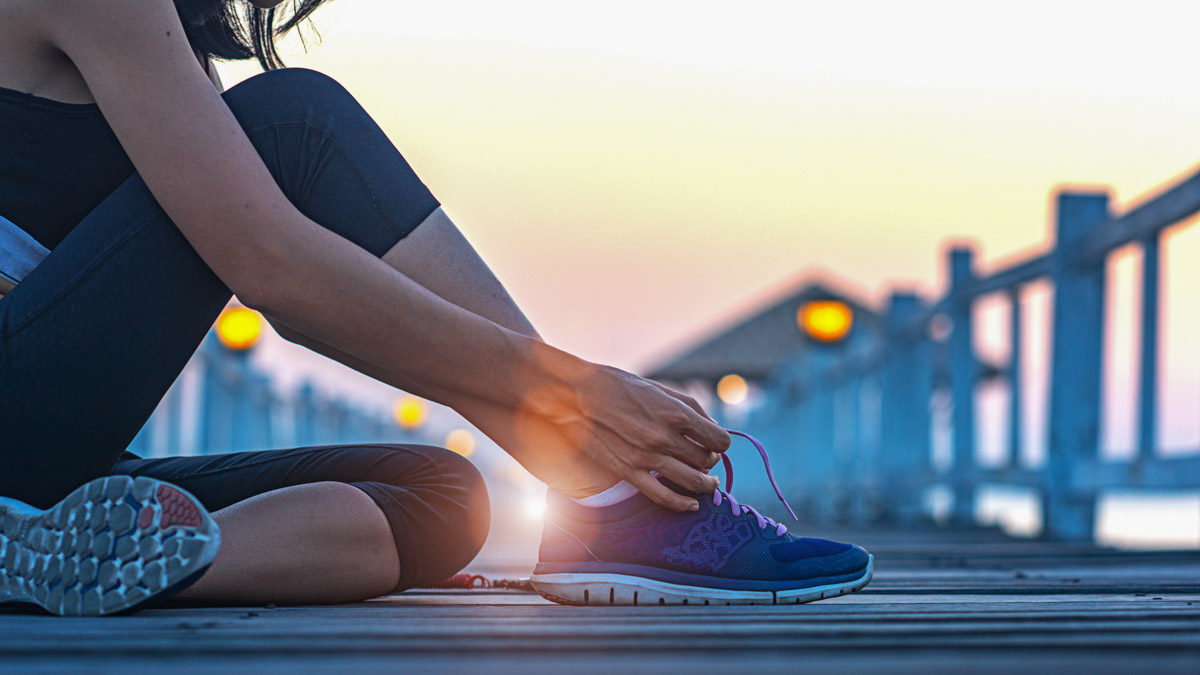 Image Of A Woman On A Wooden Dock Lacing Up Her Shoes In The Early Morning So That She Gets The Benefits Of Working Out In The Morning