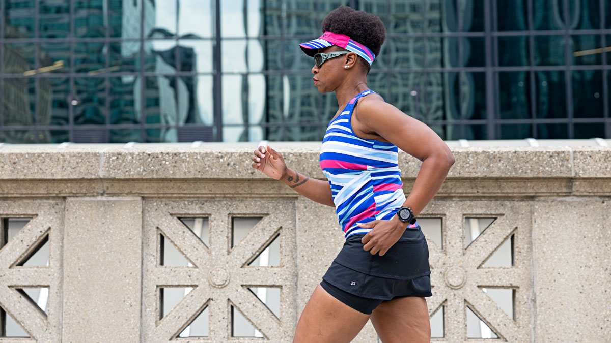 Trainingpeaks Ambassador Joy Miles Jogging On A City Street In A Brightly Colored Running Outfit And A Watch For Fitness Tracking