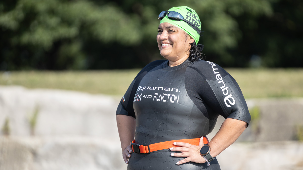 A Female Athena Triathlete Smiling In Her Wetsuit And Swim Cap On The Shore Of A Great Lake