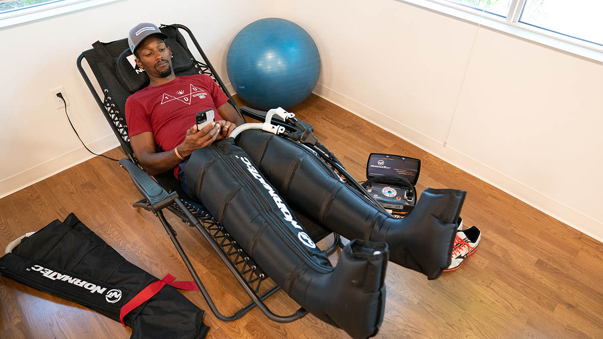 A Male Cyclist Relaxes In A Chair While Wearing Compression Leggings After A Workout