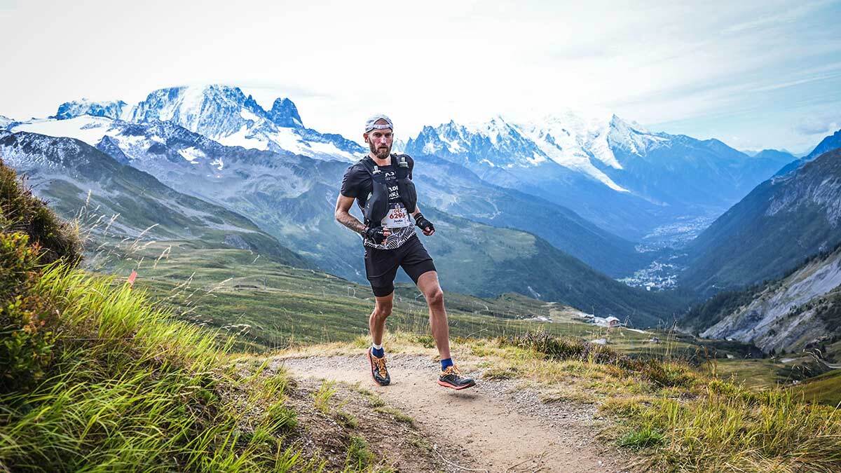 Image Of Justin Snair Running Up A Trail With Mountains In The Background