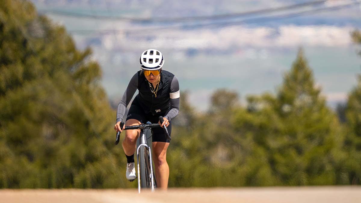 A Female Cyclist Cresting A Hill With A Vista Behind Her