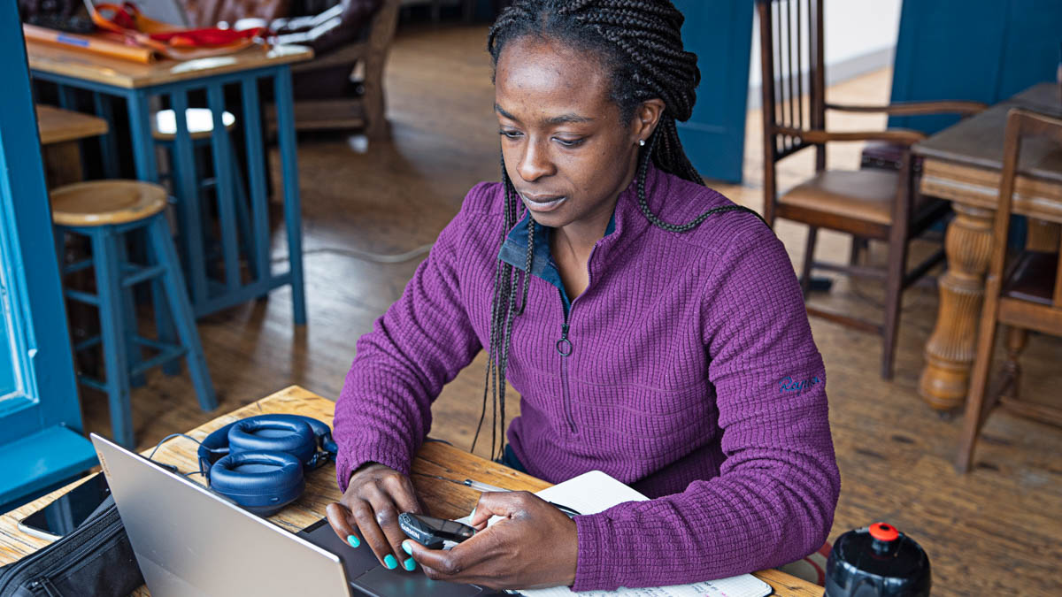 A Female Coach Working In Trainingpeaks At A Computer With A Gps Device In Hand