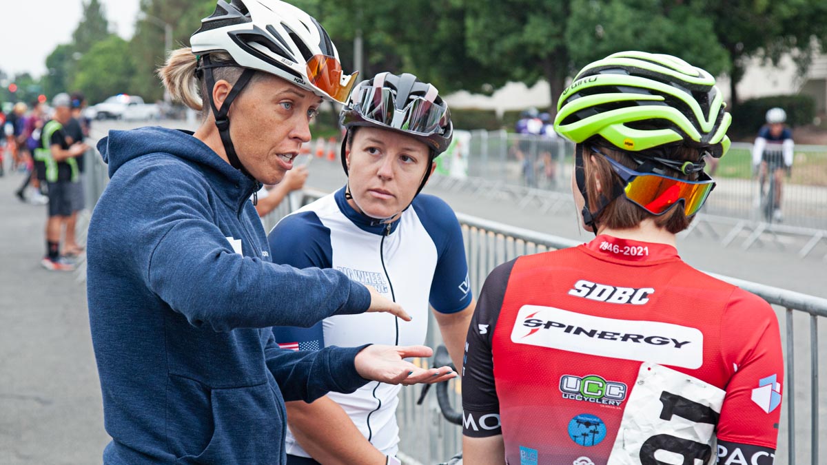 Female Coach Talking With To Bike Racers Along The Course