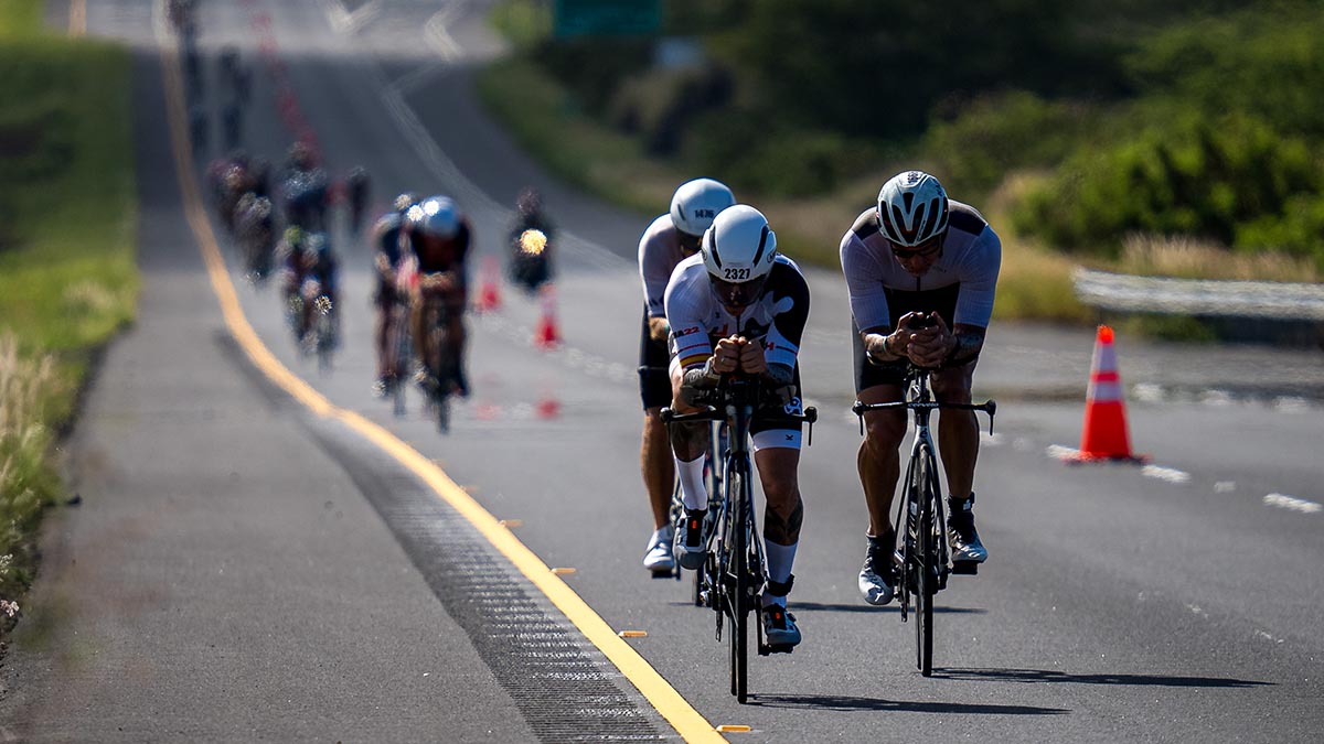 A Group Of Cyclists Race Down The Road On A Closed Course At The 2022 Ironman World Championships In Kona