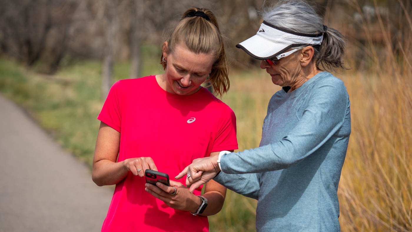 Two Women, One Younger And One Older, Look At A Smartphone And Smartwatch Before A Run.